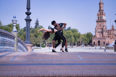 Çok ırklı genç bir çift, dışarıda şehvetle dans ederken figürler yapıyor..