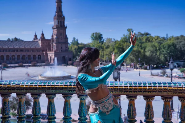 Orta yaşlı İspanyol kadın, turkuaz elbise ve elmaslar giyiyor, göbek dansı için, fayansların yanında dans ederken figürler yapıyor. Göbek dansı konsepti.