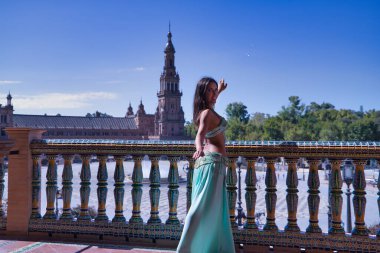 Orta yaşlı İspanyol kadın, yeşil renkli elbisesi ve yapay elmaslarıyla, göbek dansı yapıyor, fayans korkuluklarının yanında dans ederken figürler yapıyor. Göbek dansı konsepti.