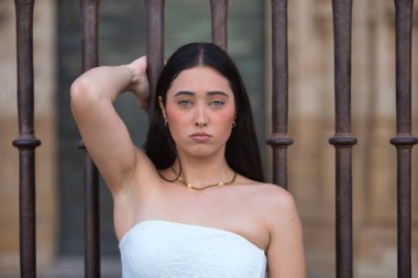 Genç, güzel, koyu saçlı, mavi gözlü, beyaz bluz giyen, sabit, delici bakışlı, korkuluğa yapışan İspanyol bir kadının portresi. Konsept: model, güzellik, moda, moda.