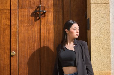 Genç, güzel, koyu renk saçlı bir kadının portresi mavi gözlü, İspanyol, siyah ceketli ve bluzlu, kot pantolonlu, mesafeye bakan. Konsept: model, güzellik, moda, moda.