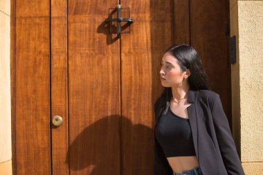 Genç, güzel, koyu renk saçlı bir kadının portresi mavi gözlü, İspanyol, siyah ceketli ve bluzlu, kot pantolonlu, mesafeye bakan. Konsept: model, güzellik, moda, moda.