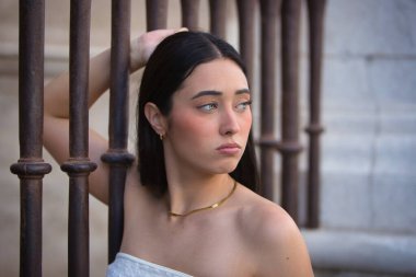 Genç, güzel, koyu saçlı, mavi gözlü, üzgün ve endişeli bakışları olan bir İspanyol kadının portresi, bir çite yapışmış, kadınlara yapılan baskıyı temsil ediyor. Konsept: model, güzellik, moda, eğilim.