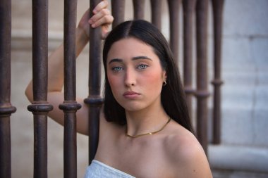 Genç, güzel, koyu saçlı, mavi gözlü, üzgün ve endişeli bakışları olan bir İspanyol kadının portresi, bir çite yapışmış, kadınlara yapılan baskıyı temsil ediyor. Konsept: model, güzellik, moda, eğilim.