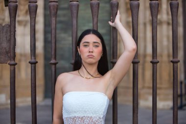 Genç, güzel, koyu saçlı, mavi gözlü, beyaz bluz giyen, sabit, delici bakışlı, korkuluğa yapışan İspanyol bir kadının portresi. Konsept: model, güzellik, moda, moda.