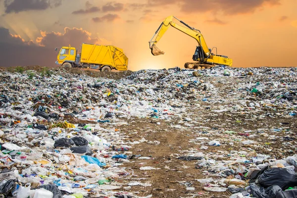 garbage dump pile in trash dump or landfill,backhoe and truck is dumping the gabage from municipal,garbage dump pile and dark sky background  ,pollution concept