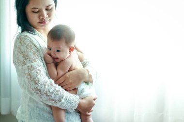 Genç anne kucaklar kucağında bebeği ikisi de yatak odasının camında..