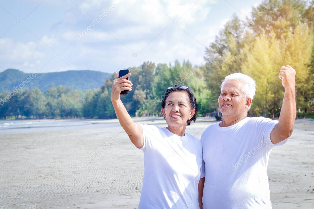 Happy, elderly couples come to the sea to relax Hold the phone, take pictures together, smile, have fun