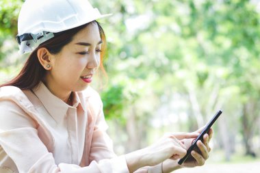 Beyaz kasklı güzel bir kadın mühendis olarak çalışıyor. Telefon etmek için cep telefonuna basın..