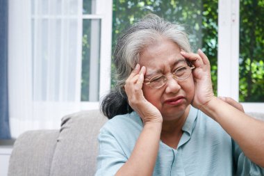 Yaşlı bir Asyalı kadının başı ağrıyor, hasta hissediyor. Evdeki kanepede otur. Kıdemli sağlık hizmetleri kavramı