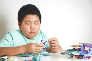 Asyalı çocuklar kendi elleriyle oyuncak yapmak için otururlar. Beyaz arkaplan