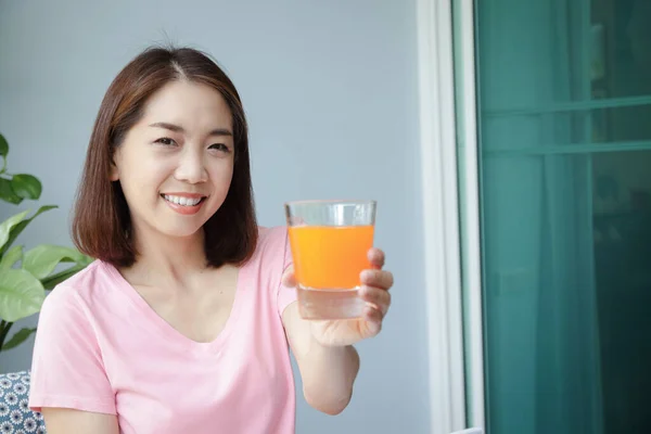 Een Gelukkige Lachende Aziatische Vrouw Met Een Glas Sinaasappelsap Zittend — Stockfoto