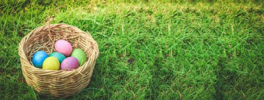 Birçok Paskalya yumurtası yeşil çimenlerin üzerine yerleştirilmiş ahşap bir sepetin içinde. Festival