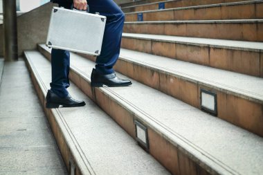 İş çantası taşıyan bir işadamı merdivenlerden ofise doğru yürüyor..