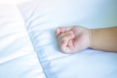 Beyaz yataktaki bebek ellerinde yer var..
