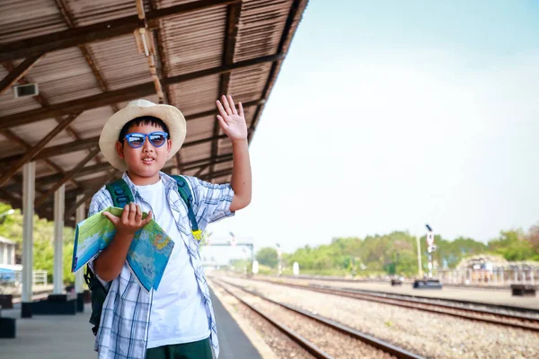 男孩拿着地图站在那里等火车来 — 图库照片