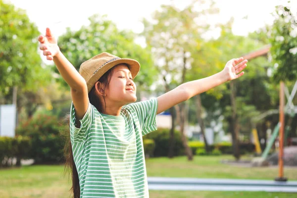 一个戴着帽子 穿着绿色衬衫的9岁女孩 站在花园里 开心地伸着胳膊 — 图库照片