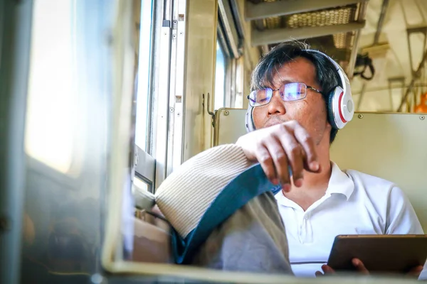 Men wearing glasses and wearing headphones Sitting eyes closed on the train Traveling alone