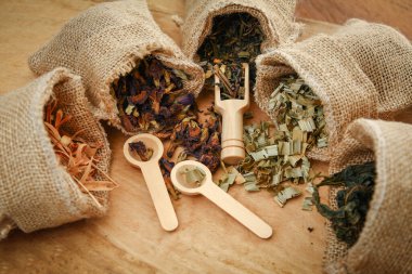 Tayland bitkisi seti. Kahverengi bir çuval içinde. Tahta zemine kaşık yerleştirilmiş birkaç torba.