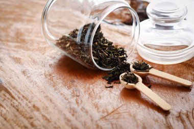 Cam bir şişede, yere tahta bir kaşık konmuş bitki çayı.