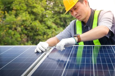 Asyalı teknisyenler güneş pillerini elektrik üretmek ve dağıtmak için kuruyorlar. Enerji teknolojisi kavramı