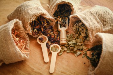 Tayland bitkisi seti. Kahverengi bir çuval içinde. Tahta zemine kaşık yerleştirilmiş birkaç torba.