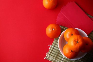 Çin Yeni Yıl kutlamalarının en iyi manzarasında portakal ve kağıt zarflar gibi meyveler vardır. Kırmızı zemine koy.