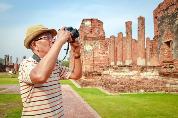 Elderly Asian Male Travelers Holding a camera to visit the ancient sites in Thailand, Ayutthaya
