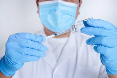 Doktorlar ya da bilim adamları hastaları tedavi etmek için COVID-19 aşısı içeren şırınga ve şişeler tutuyorlar. Tıbbi deneyler koronavirüsün yayılmasını engelliyor.