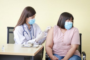 Güzel Asyalı doktorlar koronavirüsü (COVID19) obez kadınlara aşıladılar. Hastane sağlık hizmeti ve antiviral aşı kavramı
