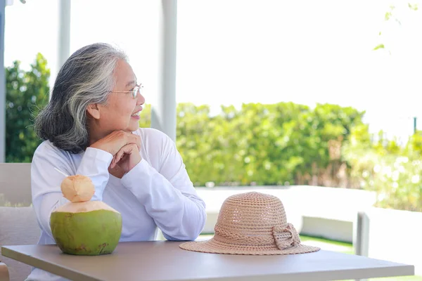 Happy Asian elderly woman wearing white shirt Sit and enjoy the cool natural breeze. The concept of tourism for the elderly, relaxing and living in retirement to be happy. copy space