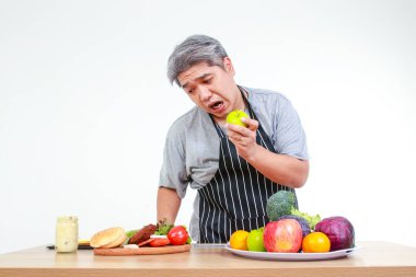 Asyalı şişman adam obeziteyi azaltmak için meyve yiyor. Yemek pişirme, kilo verme, sağlıklı yemek yeme kavramı. beyaz arkaplan