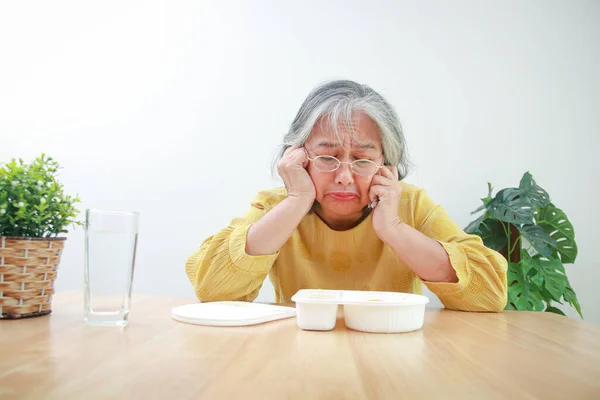 Asian old woman stay home During the coronavirus epidemic She\'s tired of boxed food. Concept of prevention of infection with the COVID-19 virus