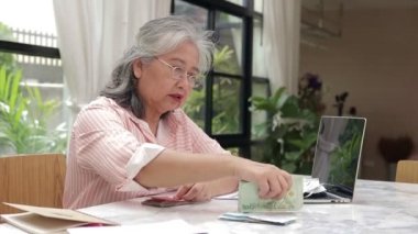 Asyalı yaşlı kadın otur ve Tayland bahtının işten kazandığı parayı say. Emeklilik, tasarruf, sigorta, emeklilik alanındaki finansal okur-yazarlık kavramı