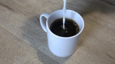 Kahve fincanına süt ekliyorum.