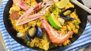 Ahşap bir masada paella dolu bir tava.