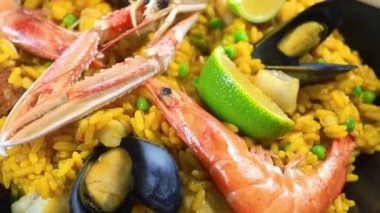 Ahşap bir masada paella dolu bir tava.