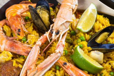 Ahşap bir masada paella dolu bir tava.