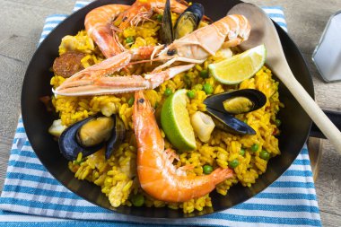 Ahşap bir masada paella dolu bir tava.