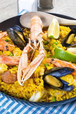 Ahşap bir masada paella dolu bir tava.