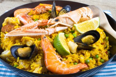 Ahşap bir masada paella dolu bir tava.