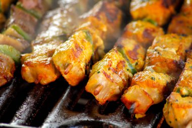 Barbeküde baharatlı tavuk şişleri.