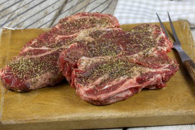 Tahtasında kuru otlar olan çiğ et.