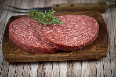 Tahta kesme tahtasının üzerinde iki kıymalı biftek..