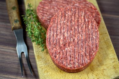 Tahta kesme tahtasının üzerinde iki kıymalı biftek..