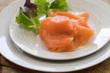 Beyaz tabakta taze marullu somon filetosu.