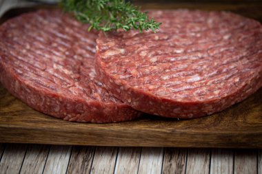 Tahta kesme tahtasının üzerinde iki kıymalı biftek..