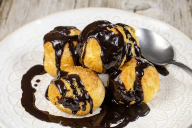 Beyaz tabakta çikolatalı profiterol..