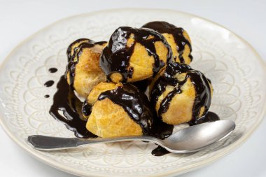 Beyaz tabakta çikolatalı profiterol..