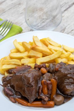 Beef Bourguignon ve beyaz tabakta patates kızartması..